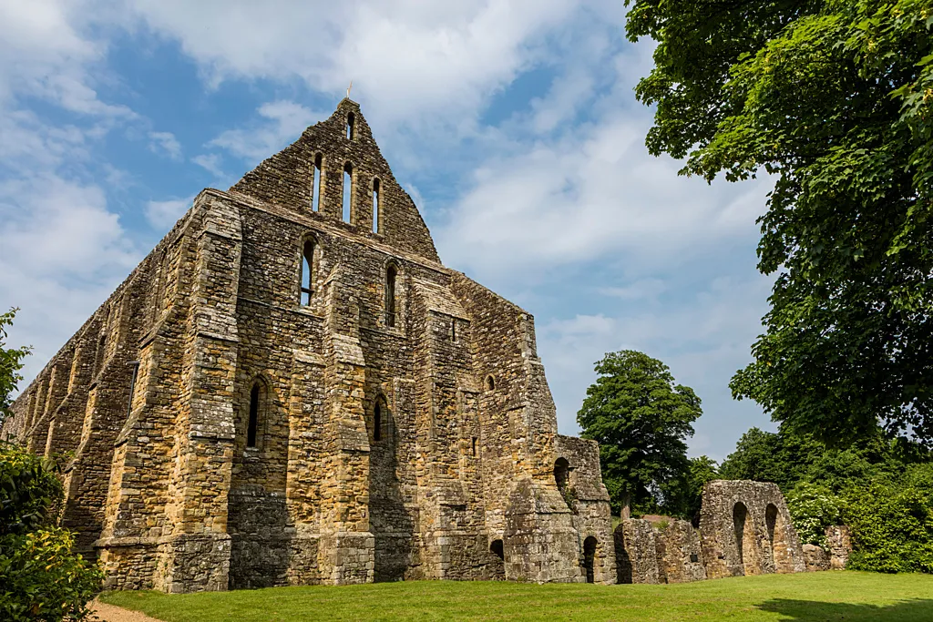 The tall gabled end of Battle Abbey's dormitory range with its lancet windows, under a summer sky