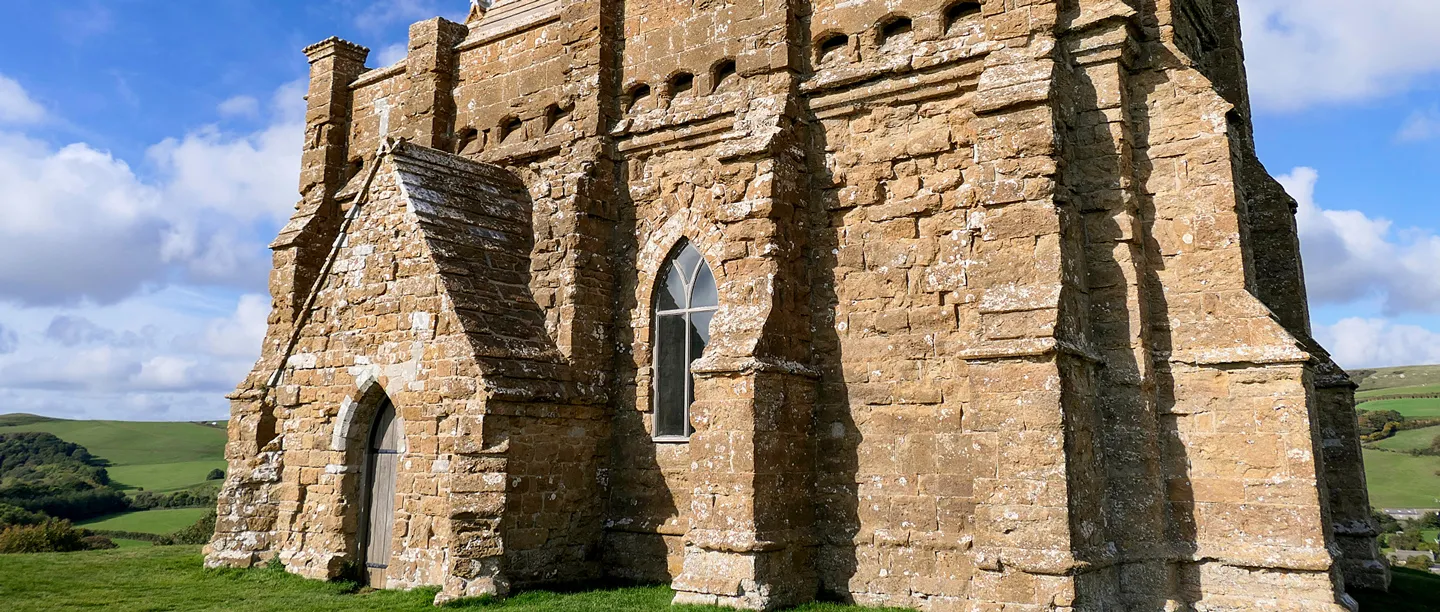 The buttressed golden stone walls and porch of St Catherine's Chapel on its hilltop above Abbotsbury