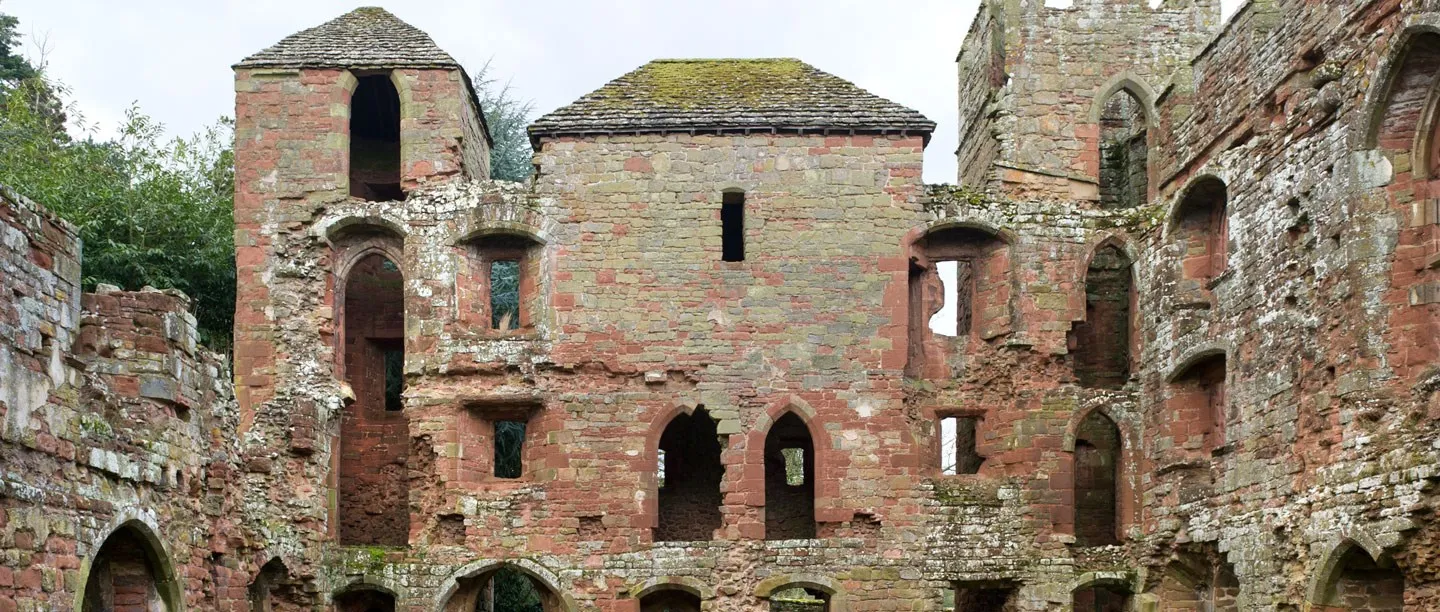 Inside the ruined shell of Acton Burnell Castle: red and grey sandstone walls, tall arched openings and two roofed towers