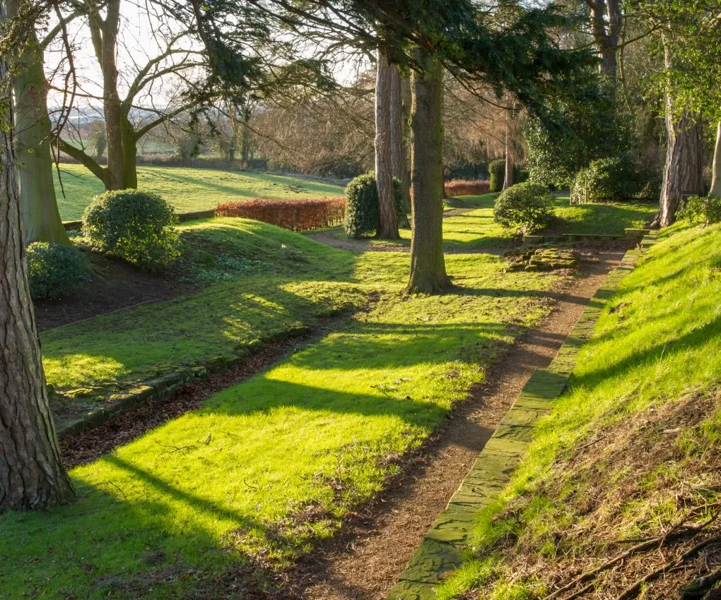 Low winter sun across the lawns and the path along Aldborough's Roman town defences, with farmland beyond