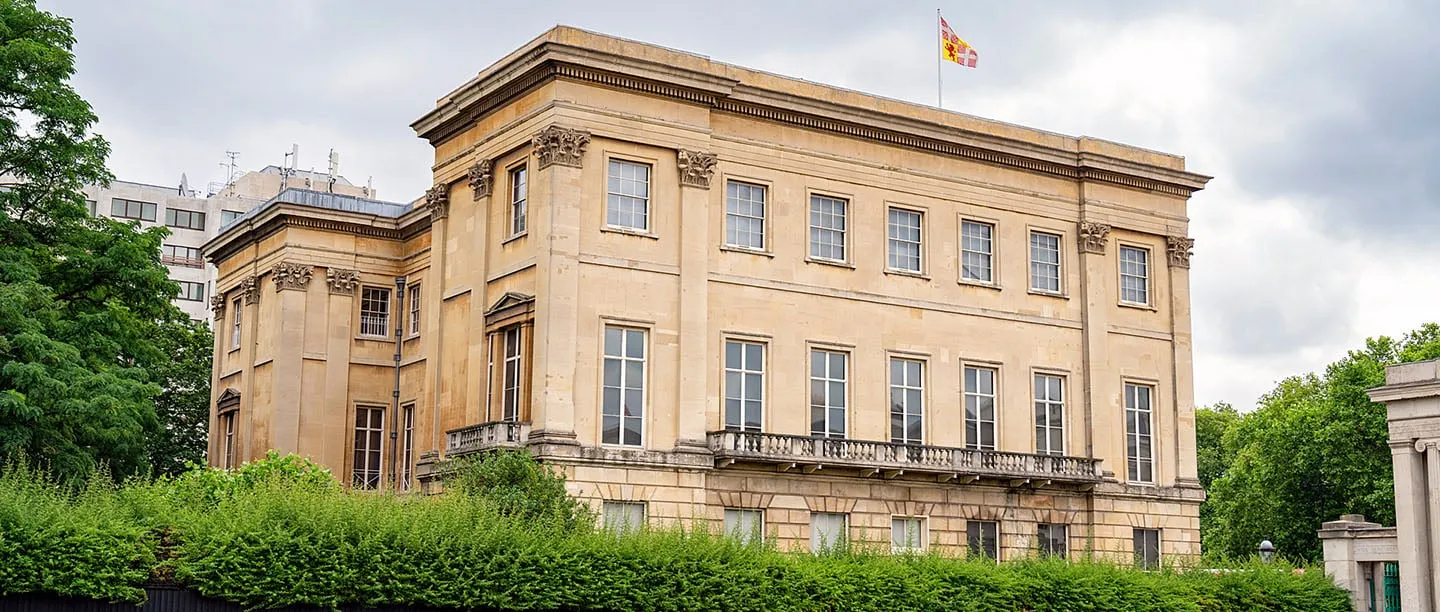 The honey-coloured stone front of Apsley House above a hedge, with the Duke of Wellington's flag on the roof