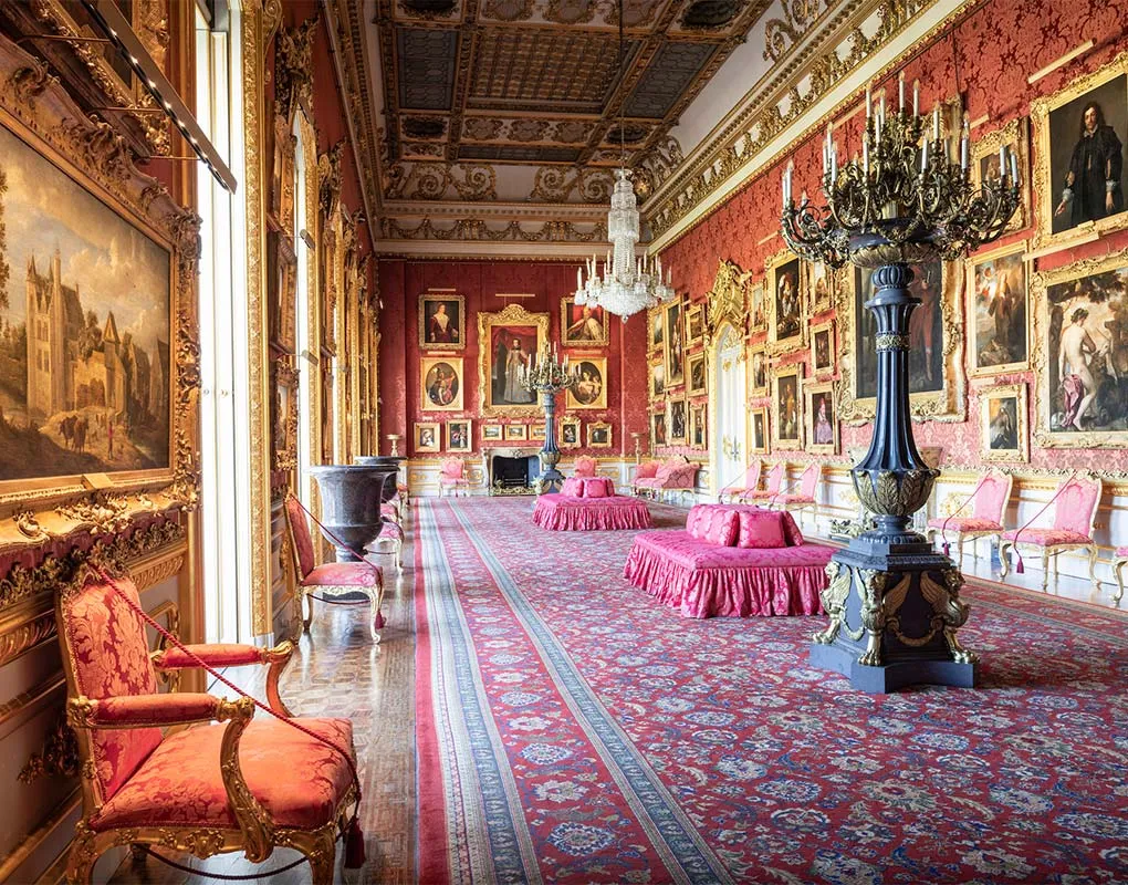 Red damask chairs and a candelabrum along the window wall of the Waterloo Gallery