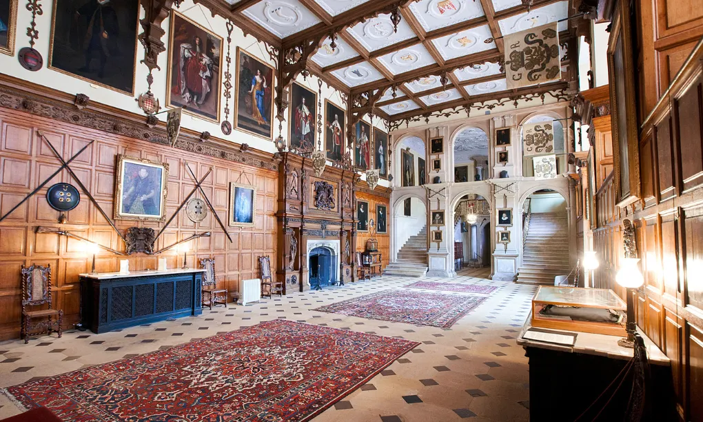 The great hall, with carved panelling, a grand staircase and portraits