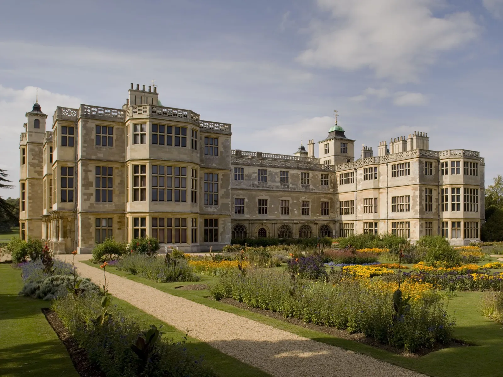 The house's long facade above the parterre's flower borders