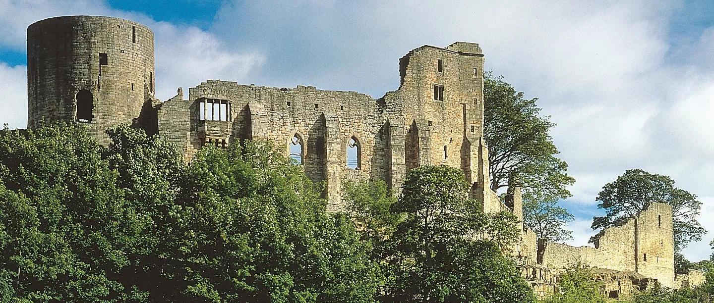The round tower and the great hall's tall windows above the trees