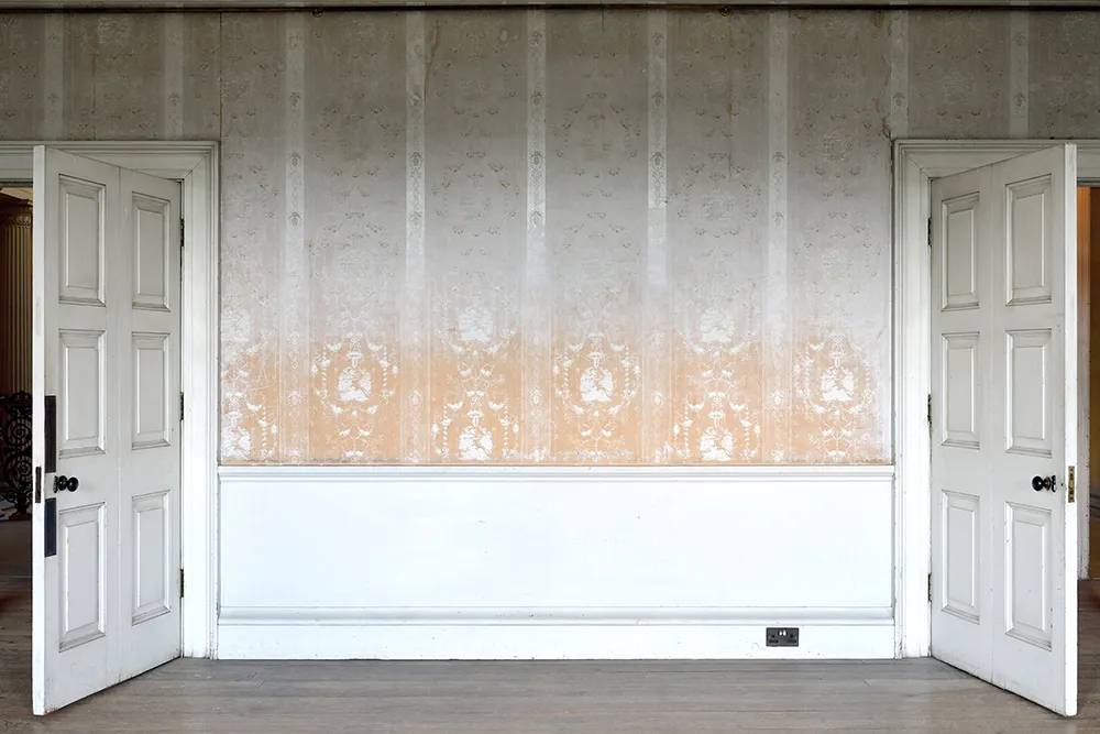 The faded wallpaper and panelled doors of the principal bedroom