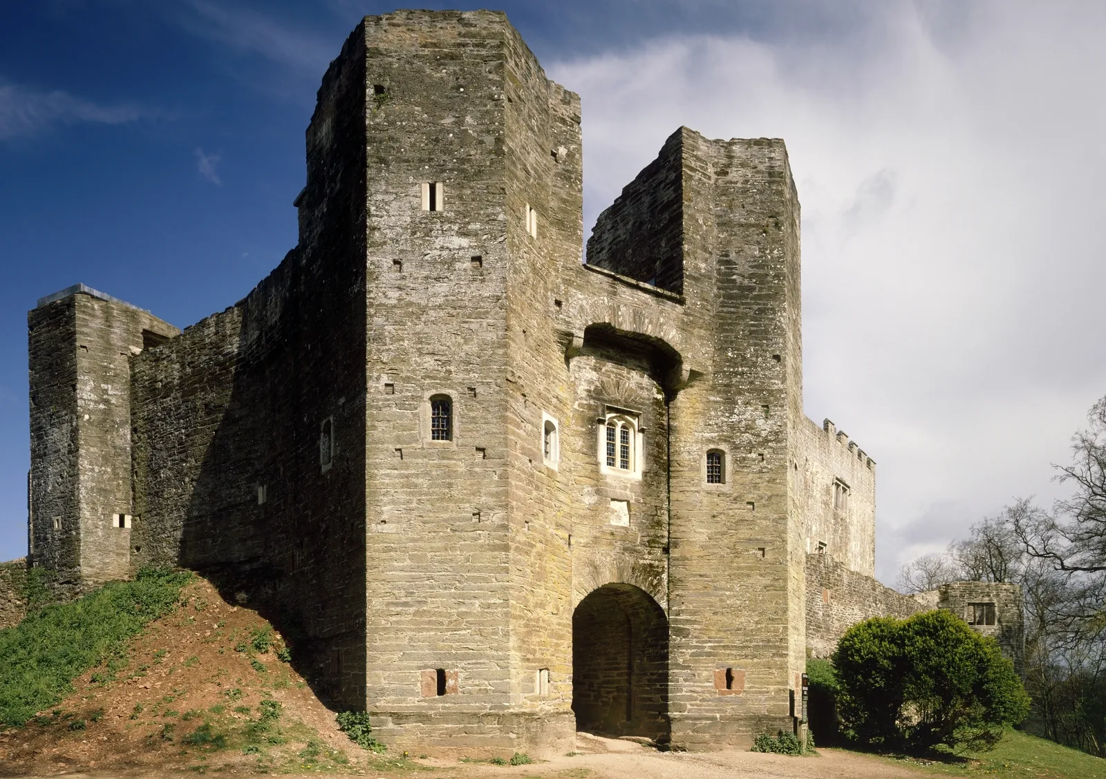 The gatehouse front with its gateway arch and a later window, against a deep blue sky