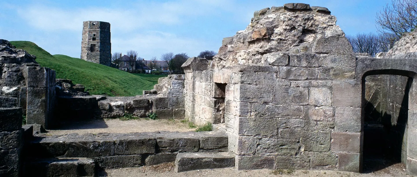 The ruined octagonal Constable Tower of Berwick Castle above a grassy bank, seen past low stone walls and steps