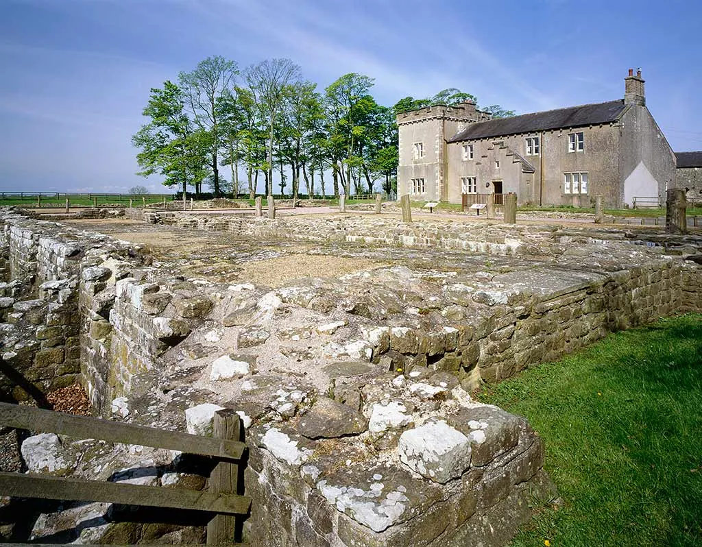Excavated Roman foundations in front of the Birdoswald farmhouse and its tower