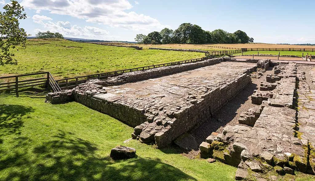 The south granary's buttressed walls and floor with fields and trees beyond