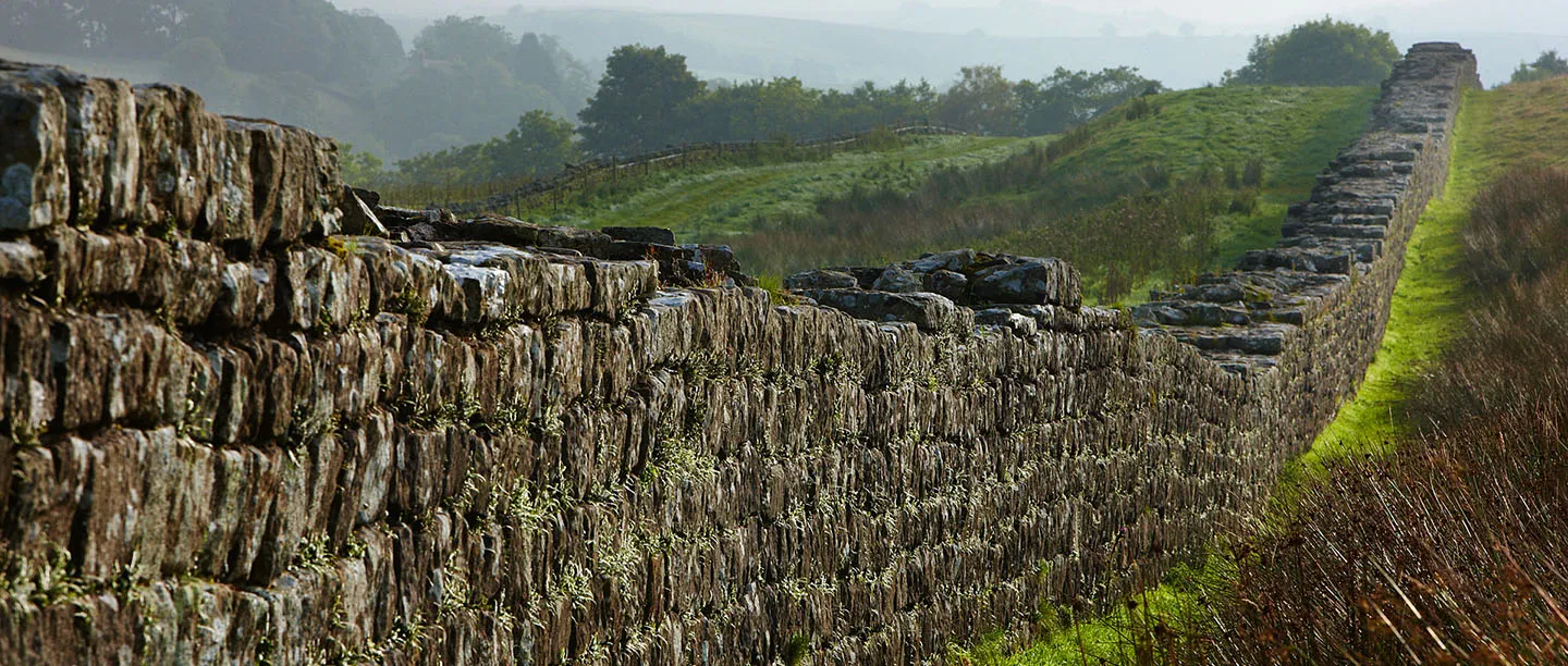 Close view of the stonework of Hadrian's Wall with misty hills beyond