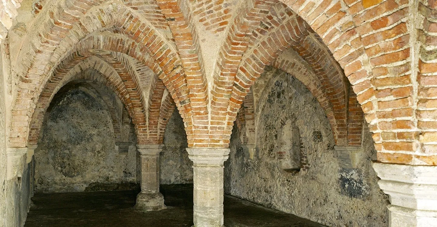 The undercroft of Blakeney Guildhall, brick rib vaults springing from stone columns over rough flint walls