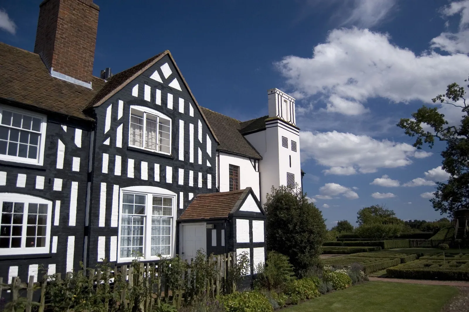 The black and white timber-framed front of Boscobel House beside its knot garden under a blue sky