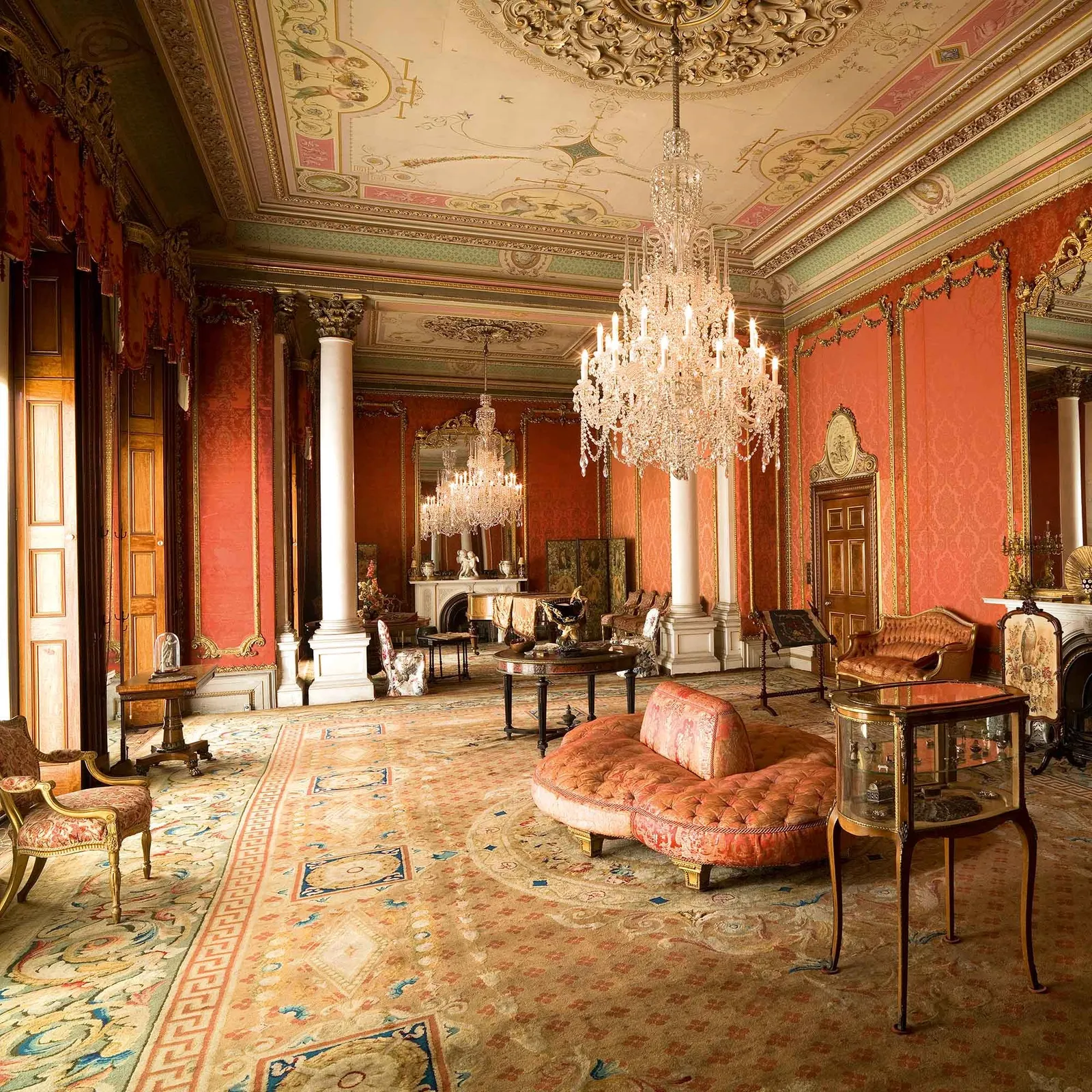 The drawing room, with red damask walls, a crystal chandelier, marble columns and a painted ceiling