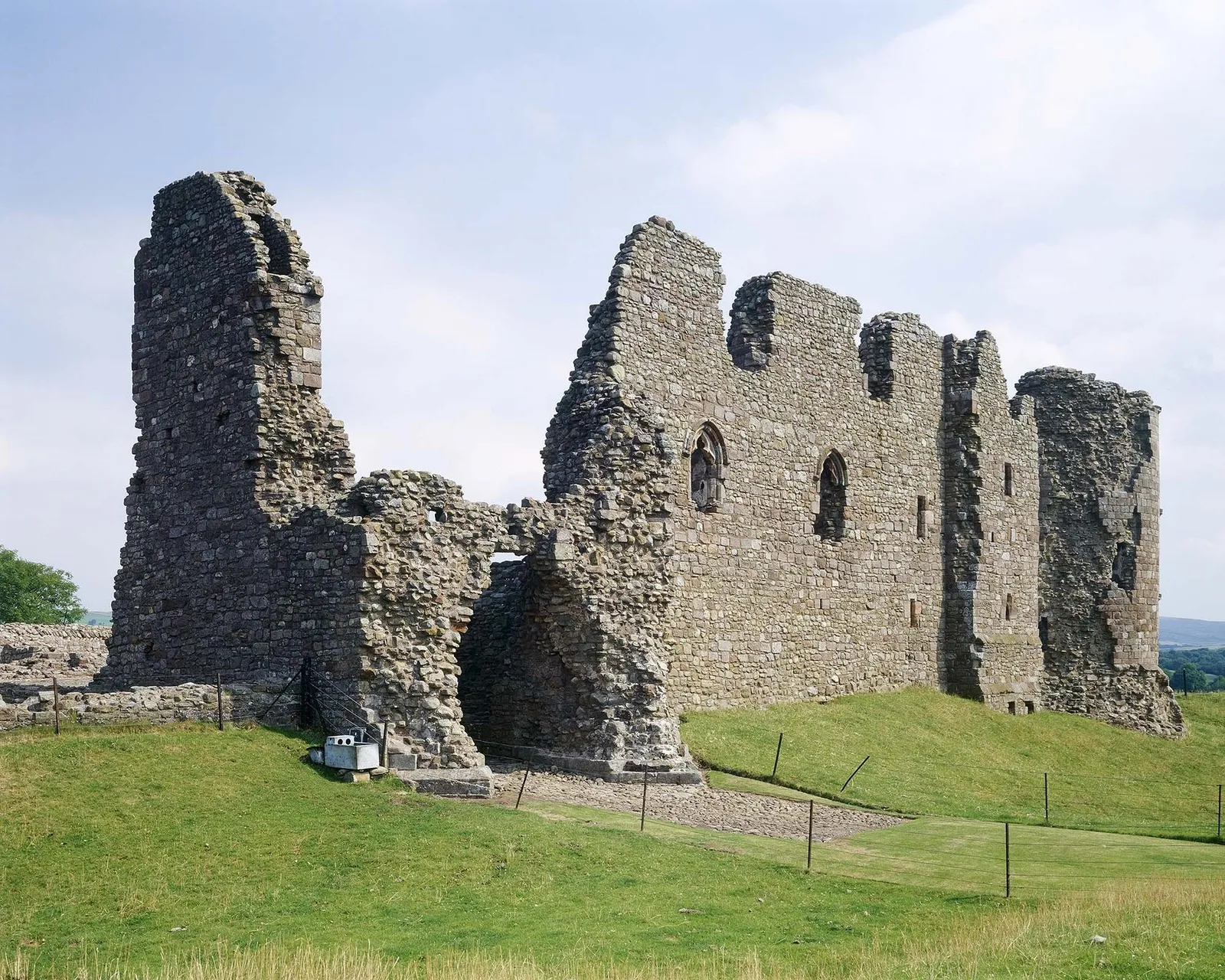 The ruined gatehouse and curtain wall of Brough Castle above the grassy ditch