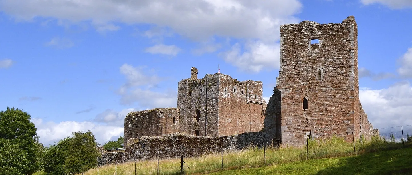 The ruined south-west tower and curtain wall of Brougham Castle under a blue sky