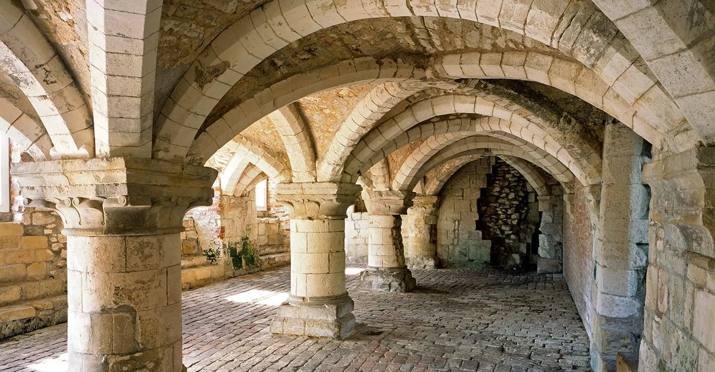 The Norman vaulted undercroft of Burton Agnes Manor House, with round stone pillars, carved capitals and a cobbled floor