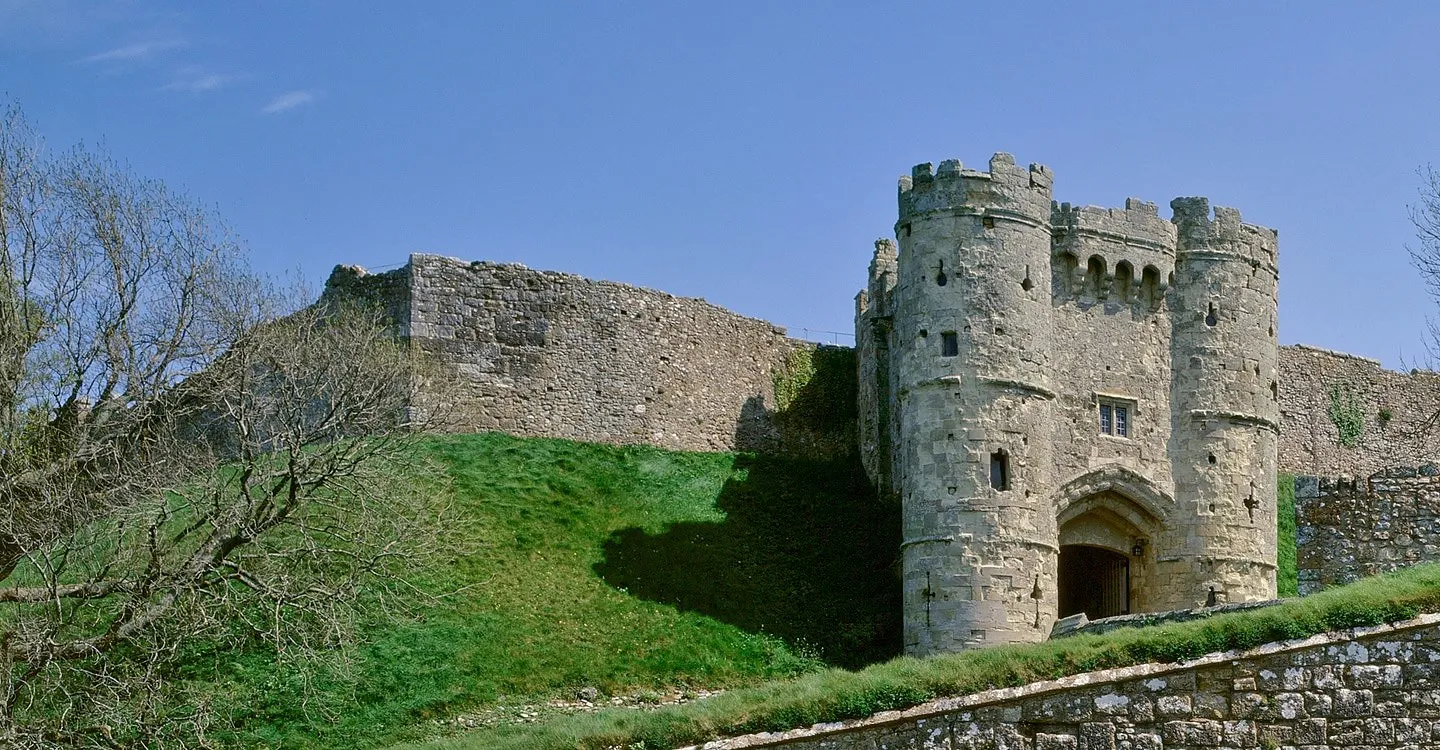 The twin-towered gatehouse above a grassy bank under a blue sky