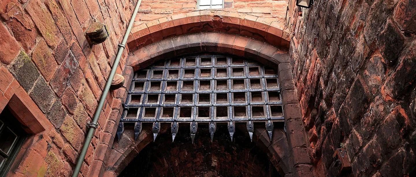 Looking up at the iron portcullis in a sandstone arch