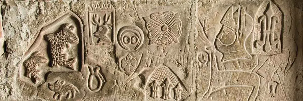 Medieval carvings cut into the stone of the keep: animals, a flower, heraldry and a bishop