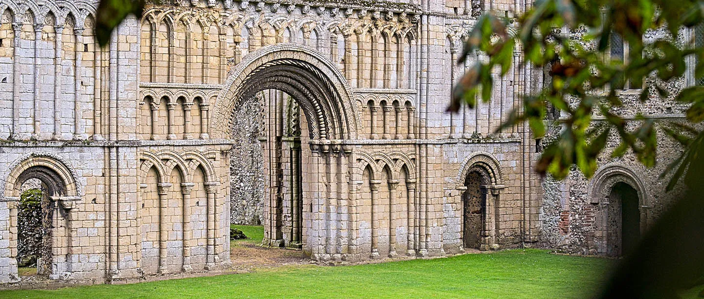 The tiers of blind arcading on the west front of the priory church, seen through leaves