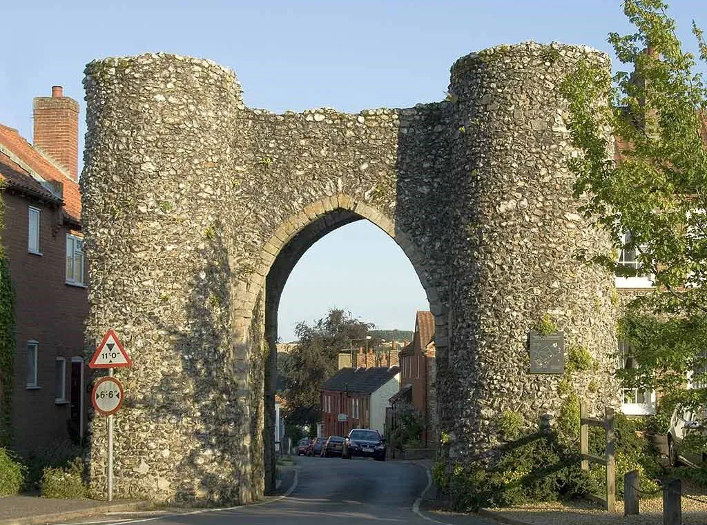 The Bailey Gate at Castle Acre, a flint gatehouse with two round towers and a pointed arch over the village street