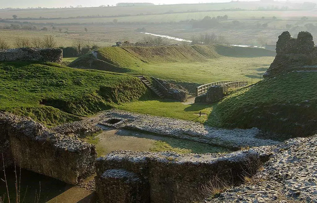 Frosty flint foundations in Castle Acre's inner bailey looking across earthworks, steps and a footbridge to the river valley