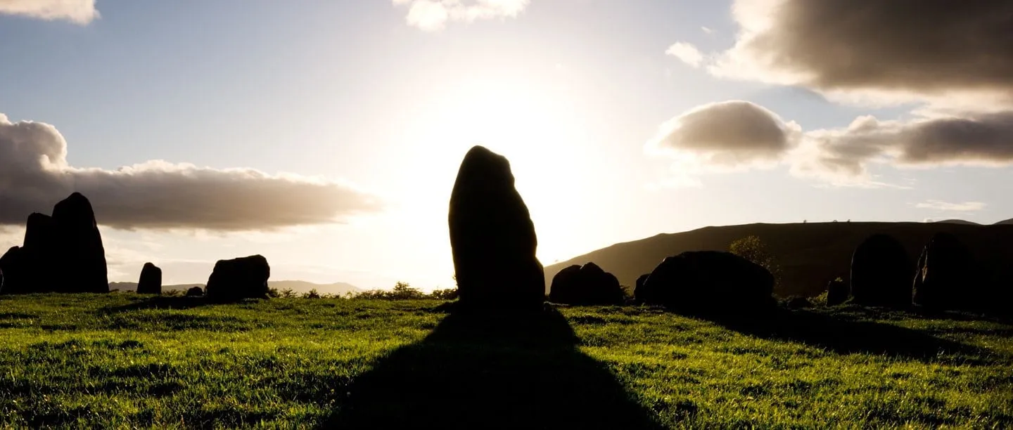 Standing stones in silhouette against a low sun