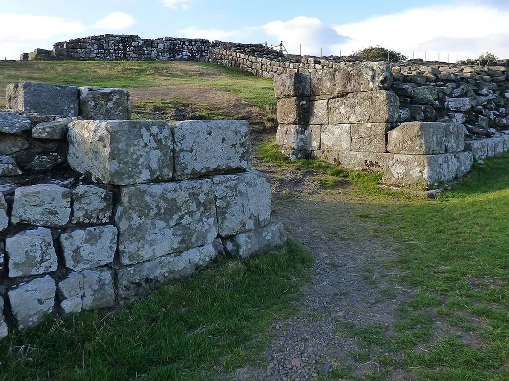 The massive dressed stones of the north gateway of Milecastle 42 at Cawfields, with Hadrian's Wall behind