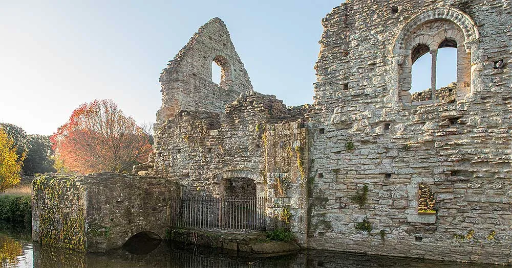 The Norman House at Christchurch above the mill stream, with its round-arched window and an autumn tree
