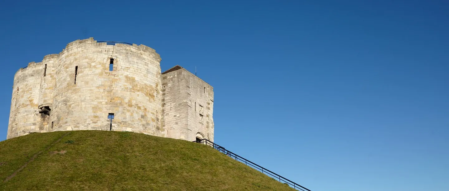 The quatrefoil keep on its grassy motte under a deep blue sky