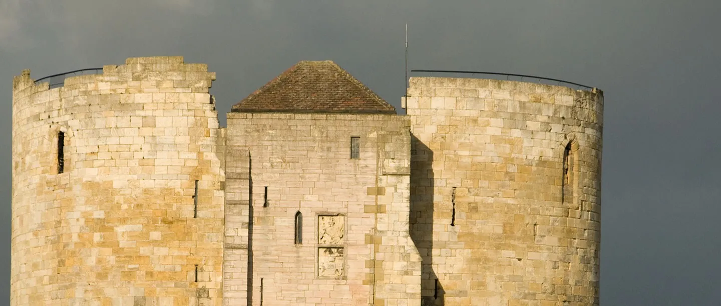 Sunlit stone of the keep against a dark storm sky