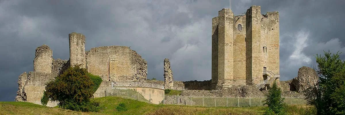 The keep and its outside stair in sunlight against a stormy sky