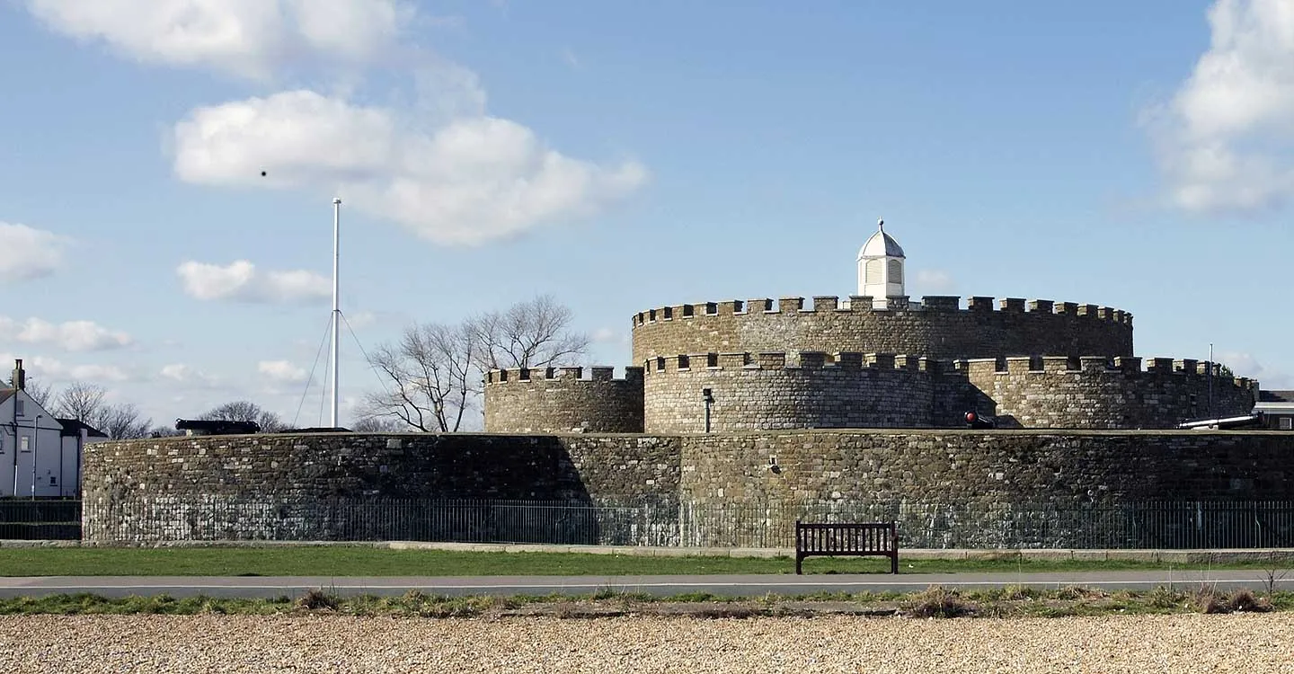 The low rounded bastions and central tower seen across the shingle from the seafront