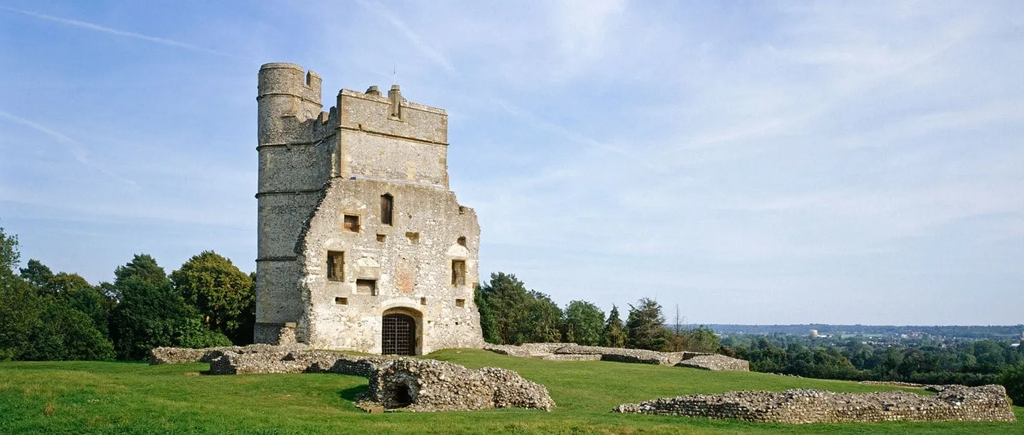 Donnington Castle's ruined gatehouse and the low flint walls of the castle on a sunny hilltop