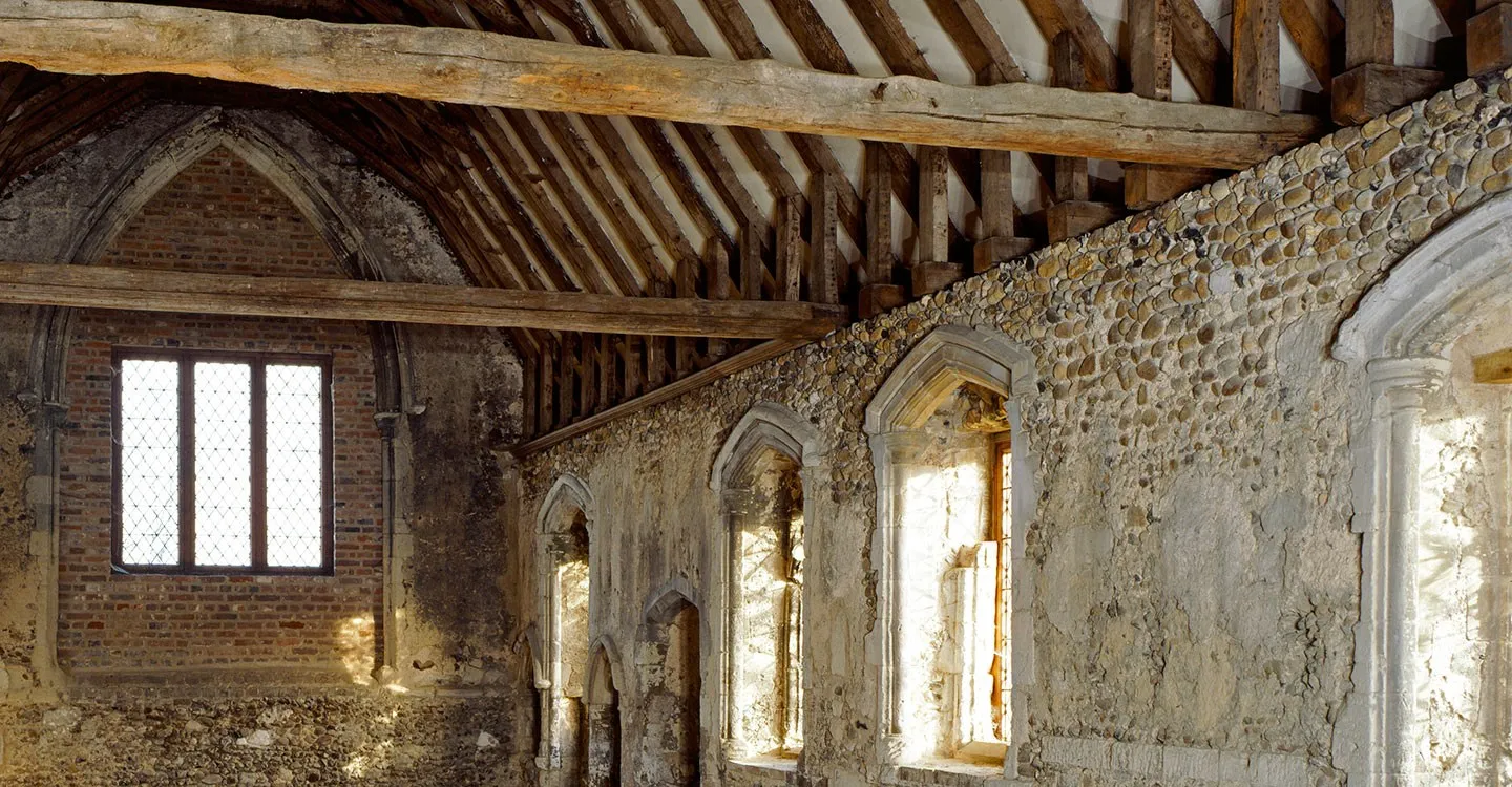 Inside Duxford Chapel, a timber roof over flint and plaster walls with pointed lancet windows lit by bright sun