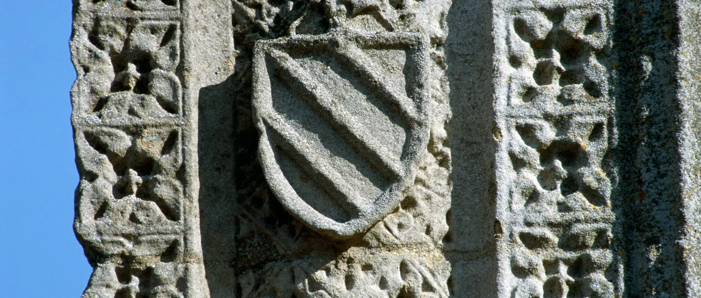 A carved heraldic shield and diaper pattern on the stonework of the Eleanor Cross at Geddington