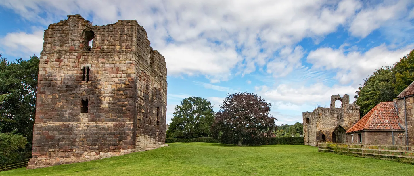 Etal Castle's residential tower and the ruined gatehouse across the lawn, with a red-roofed cottage