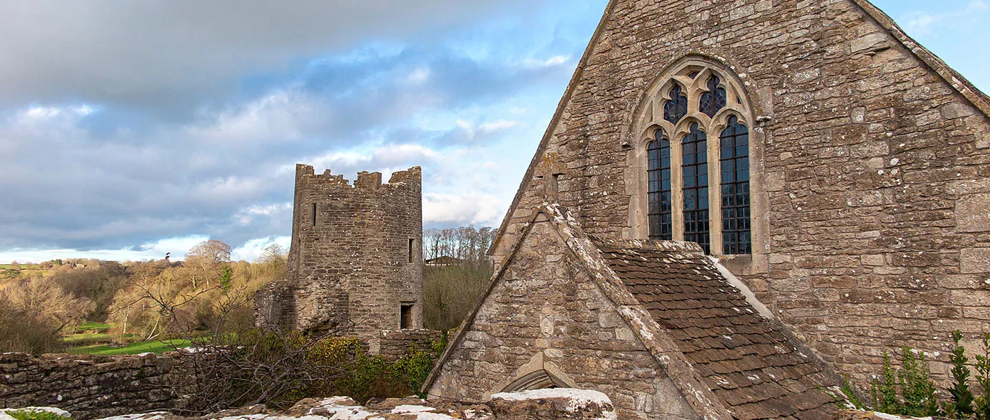 A round tower of Farleigh Hungerford Castle and the chapel gable under a stormy winter sky
