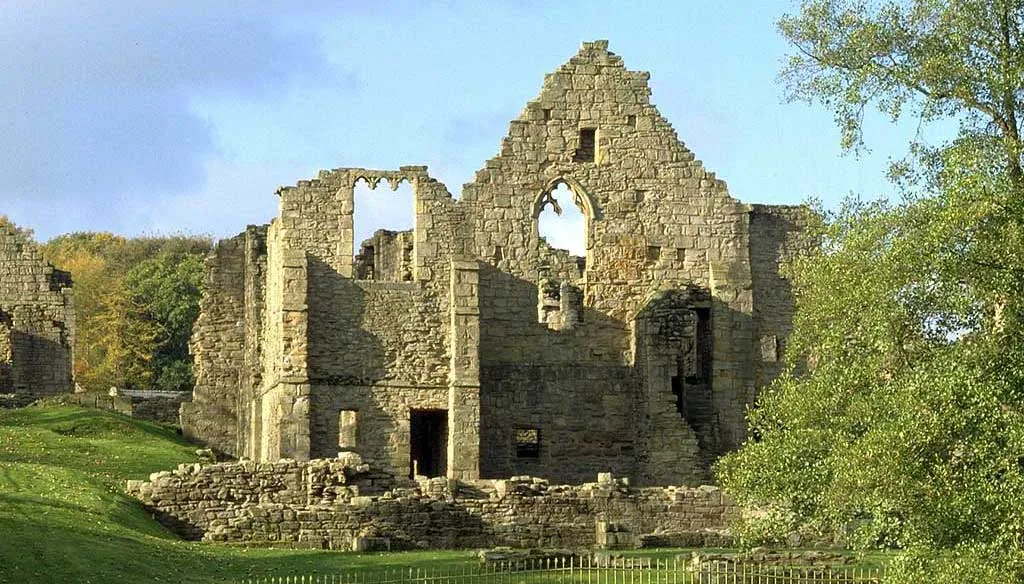 The ruined gable and walls of the prior's house at Finchale Priory among autumn trees