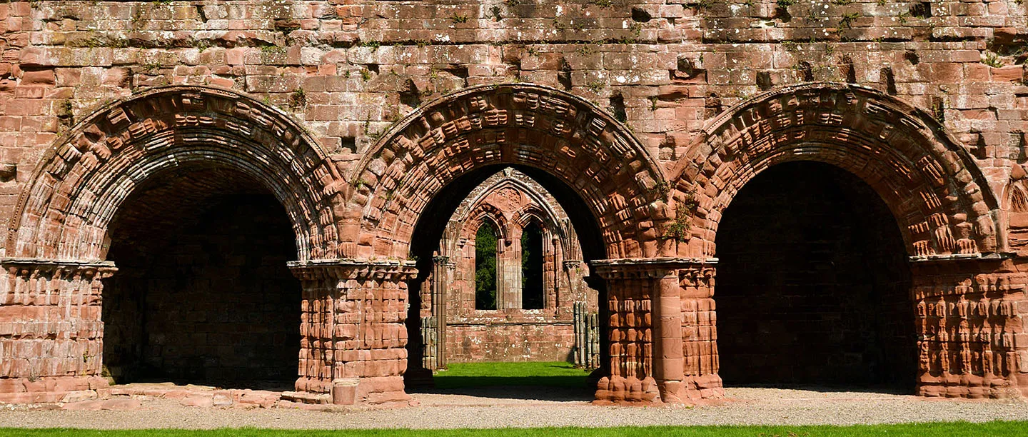 The carved round arches of Furness Abbey's chapter house entrance in red sandstone