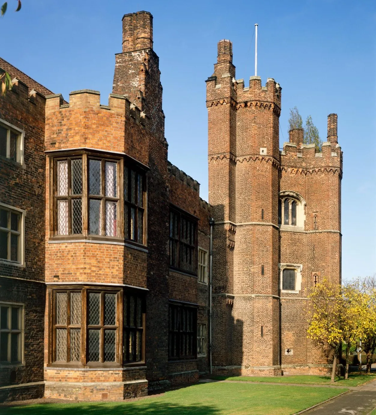 The tower and a great bay window against a blue sky, with an autumn tree