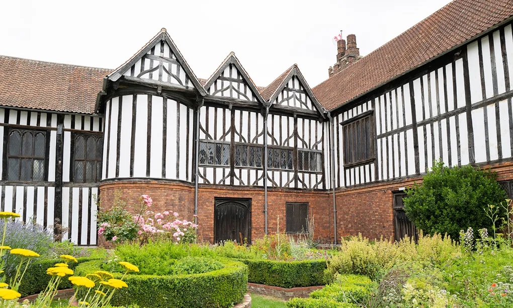 The timber-framed great hall range above a knot garden in flower