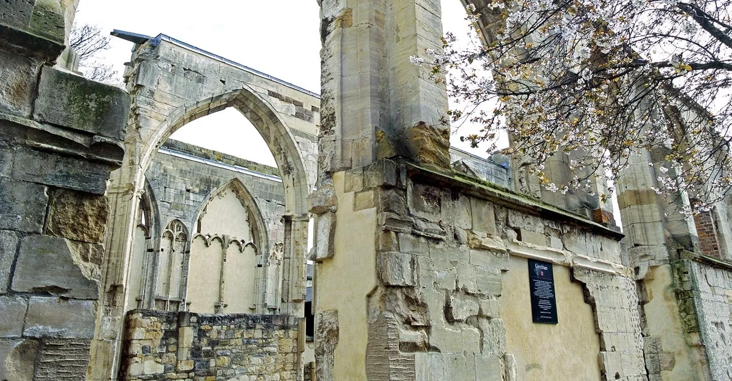 Ruined Gothic arches and window tracery at Greyfriars, Gloucester, with a cherry tree in blossom