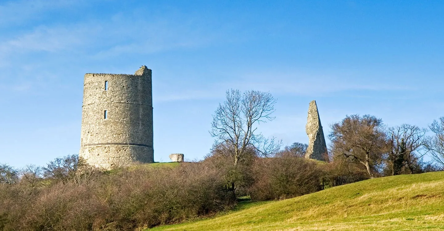 The ruined round tower of Hadleigh Castle and a fragment of a second tower above a grassy slope