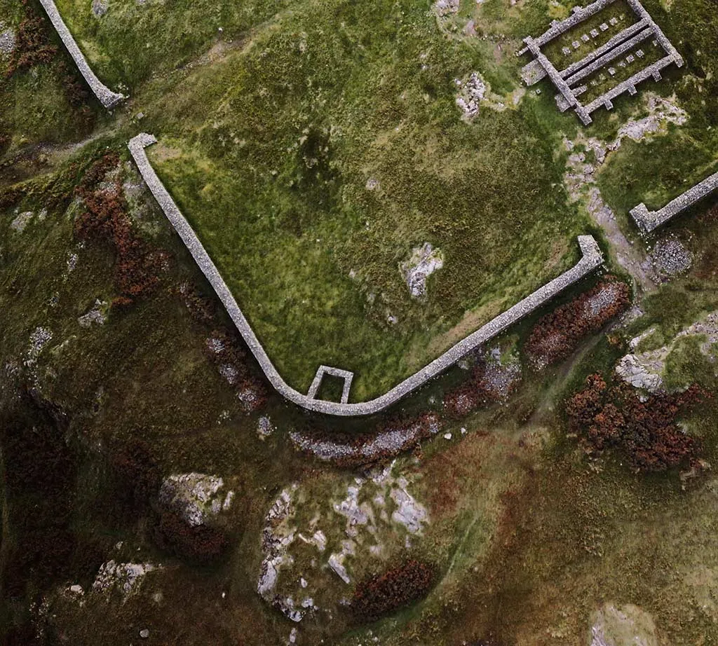 Aerial view of a corner of Hardknott fort's wall and its gateway, with the granary beyond