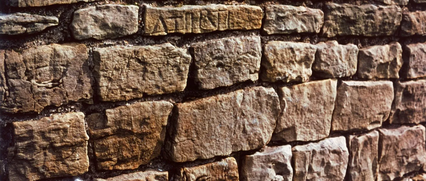 Close-up of Hadrian's Wall at Harrows Scar, with Roman lettering carved into one of the squared sandstone blocks