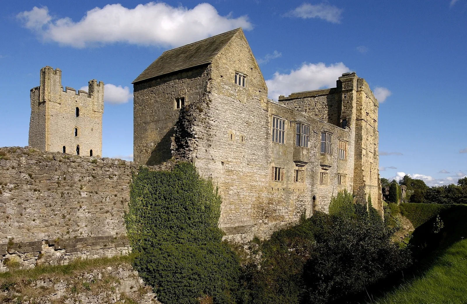 The ruined east tower rising behind the curtain wall, beside the Tudor west range