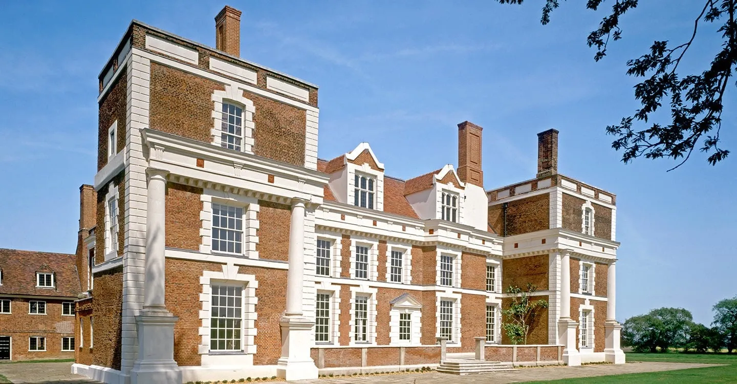 Hill Hall, an Elizabethan brick mansion with white stone dressings, giant columns and tall chimneys, under a blue sky