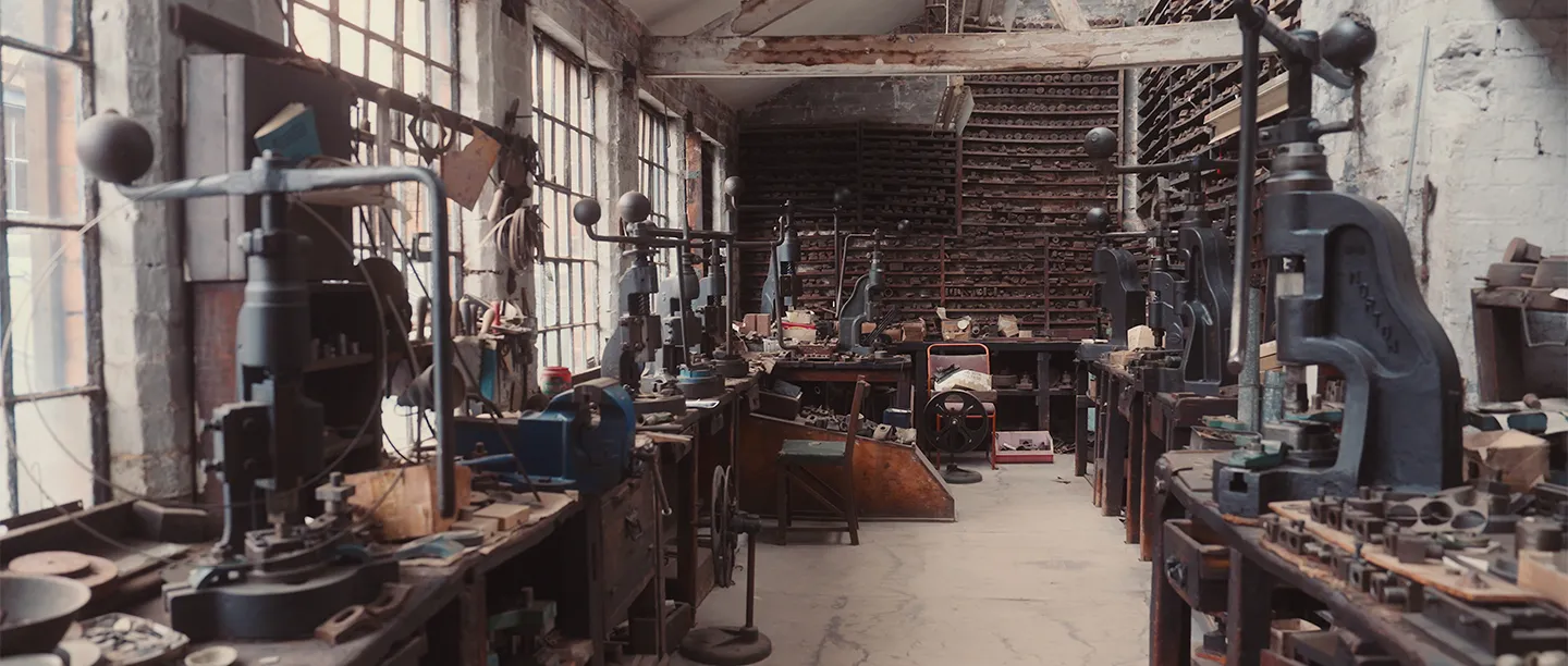 The press shop at JW Evans Silver Factory, with fly presses along the benches and racks of dies on the far wall